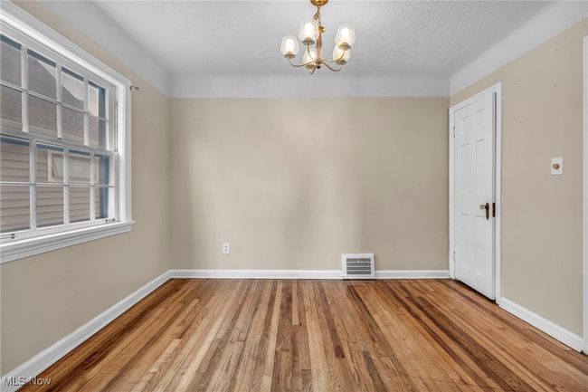Unfurnished dining area with wood finished floors, visible vents, baseboards, and an inviting chandelier | Image 29
