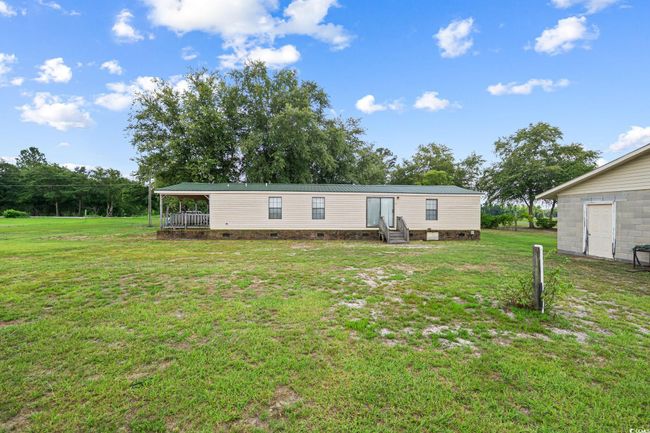 Rear view of property with entry steps, a lawn, crawl space, and a metal roof | Image 29