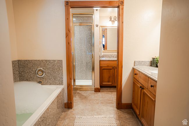 Full bath featuring a stall shower, a garden tub, vanity, and tile patterned floors | Image 18