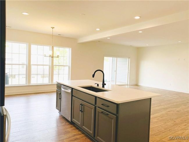 Kitchen featuring dishwasher, a sink, open floor plan, light wood-type flooring, and light countertops | Image 31