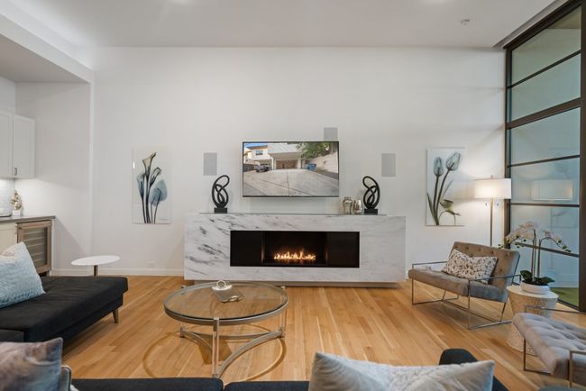 Living room featuring beverage cooler, wood finished floors, and a fireplace | Image 7