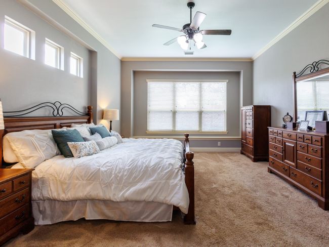 The primary bedroom is situated on ground level and includes a high ceiling, a ceiling fan, and a window seat. | Image 15