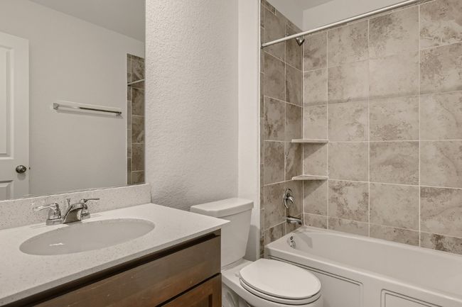 Bathroom featuring toilet, vanity, shower / bathtub combination, and a textured wall | Image 13