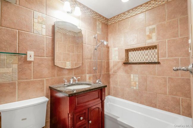 Full bath with vanity, tile walls, toilet, and shower / washtub combination | Image 13