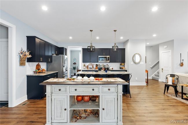 Kitchen with a kitchen island with sink, baseboards, appliances with stainless steel finishes, and light wood-style flooring | Image 17
