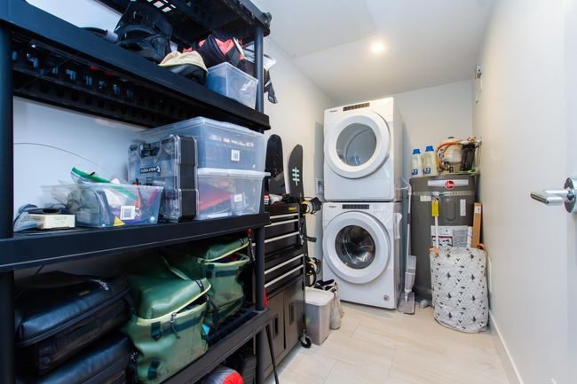 Washroom featuring stacked washer / drying machine, laundry area, water heater, and baseboards | Image 13