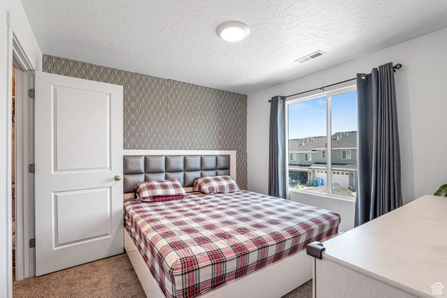 Bedroom with carpet floors, a textured ceiling, and wallpapered walls | Image 29