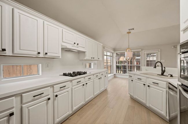 Kitchen featuring a sink, white cabinetry, under cabinet range hood, and black gas stovetop | Image 17