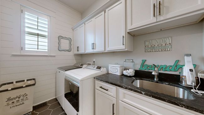 Laundry room located off the master bedroom closet—complete with custom cabinetry, shiplap detail, a deep sink, and stylish flooring to keep chores efficient and tucked away. | Image 53