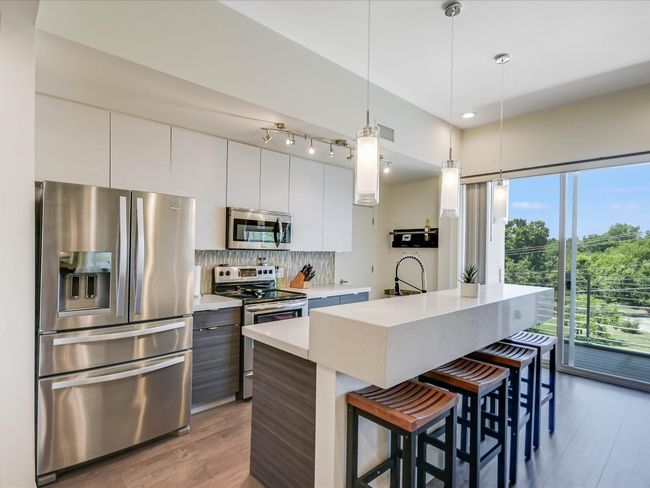 Kitchen featuring appliances with stainless steel finishes, modern cabinets, a breakfast bar, tasteful backsplash, and recessed lighting | Image 12