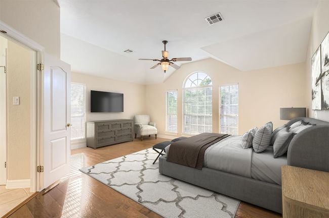 Bedroom with vaulted ceiling, baseboards, visible vents, a ceiling fan, and wood finished floors | Image 23