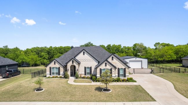 French provincial home with a detached garage, stone siding, fence, a front yard, and brick siding | Image 38