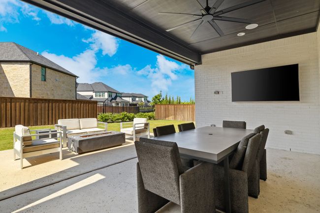 View of patio featuring a fenced backyard, an outdoor living space with a fire pit, a ceiling fan, outdoor dining area, and a residential view | Image 40