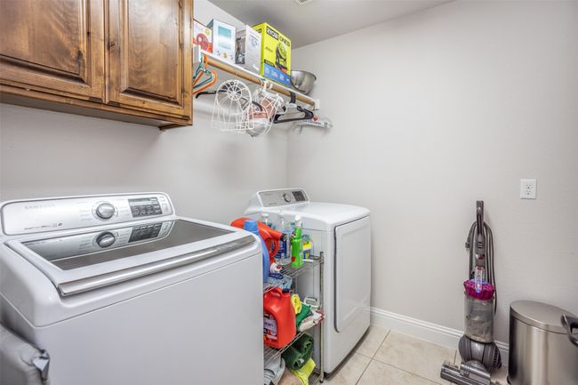 Laundry room featuring separate washer and dryer, cabinet space, and light tile patterned flooring | Image 7