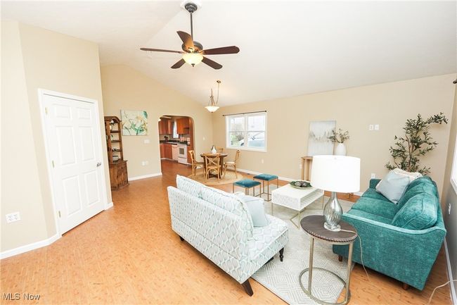 Living area featuring light wood-type flooring, ceiling fan, arched walkways, baseboards, and lofted ceiling | Image 6