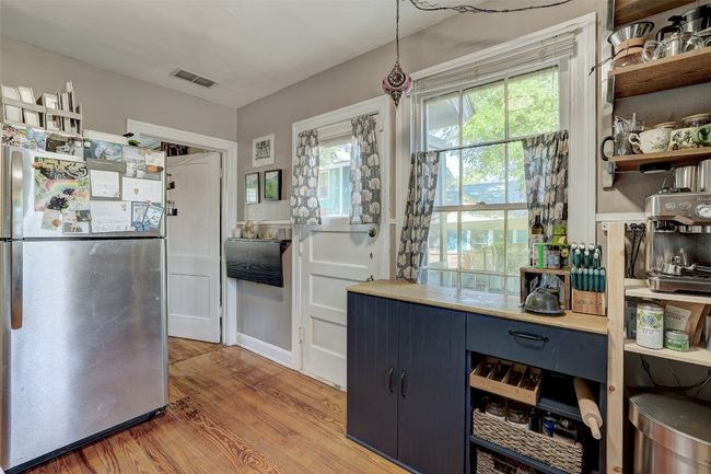Kitchen featuring a wealth of natural light, light wood-type flooring, freestanding refrigerator, visible vents, and open shelves | Image 14