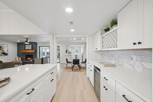 Kitchen featuring a fireplace, wine cooler, light wood-type flooring, white cabinetry, and recessed lighting | Image 18