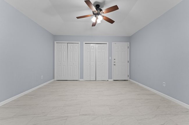 Unfurnished bedroom with multiple closets, light marble finish flooring, and ceiling fan | Image 23