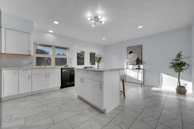 Kitchen with black dishwasher, a center island, white cabinetry, recessed lighting, and a breakfast bar area | Image 16