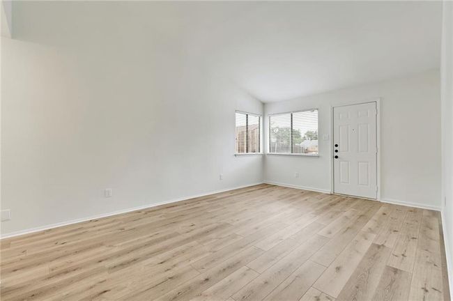 Empty room featuring light wood-type flooring, vaulted ceiling, and baseboards | Image 5