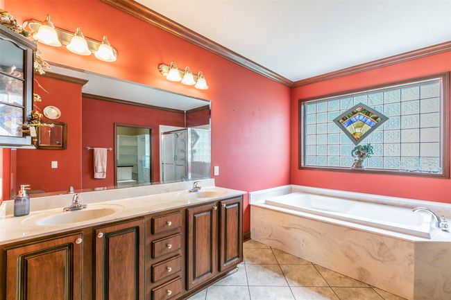 Bathroom with tile patterned flooring, a garden tub, double vanity, ornamental molding, and a sink | Image 13