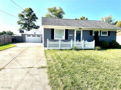 Single story home featuring a garage, a front lawn, and an outbuilding | Image 1