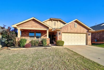 Craftsman-style house featuring a front lawn, a porch, and a garage | Image 1