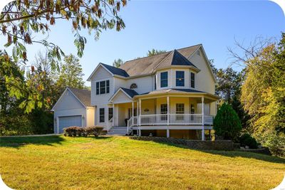 View of front of property featuring a porch, a front yard, and a garage | Image 1