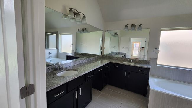 Bathroom featuring a bath, double vanity, vaulted ceiling, tile patterned flooring, and a shower | Image 21
