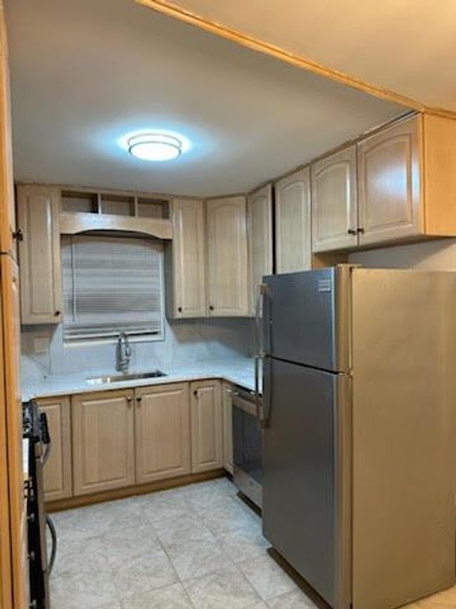 Kitchen with light brown cabinets, a sink, range, light countertops, and freestanding refrigerator | Image 5