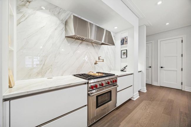 [Kitchen] Curated kitchen upgraded with statement making Neolith calacatta gold backsplash and countertop, Wolf 4 burner range with center griddle, convection oven, and smartly designed SieMatic soft closing cabinets for ease of organization | Image 12
