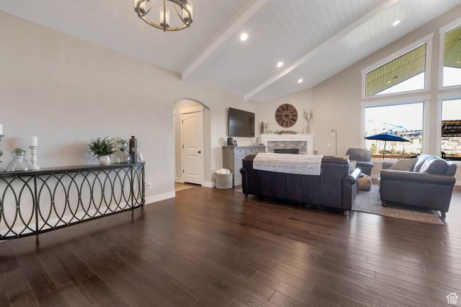 Living area featuring arched walkways, dark wood-type flooring, a fireplace, and beamed ceiling | Image 7