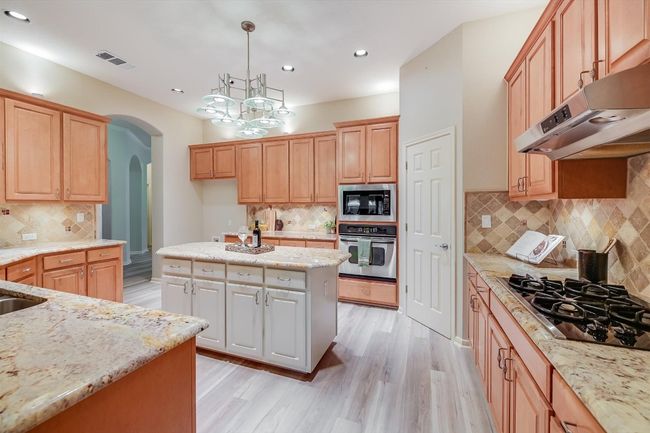 Kitchen featuring stainless steel oven, black gas cooktop, built in microwave, range hood, and tasteful backsplash | Image 20