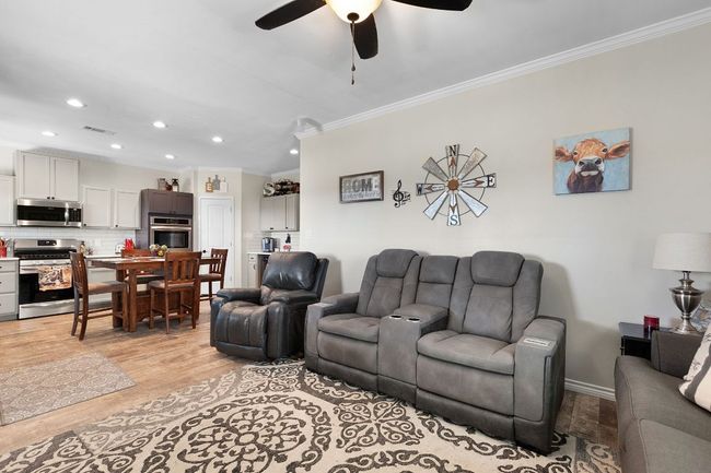 Living area with light wood finished floors, visible vents, ornamental molding, recessed lighting, and a ceiling fan | Image 10