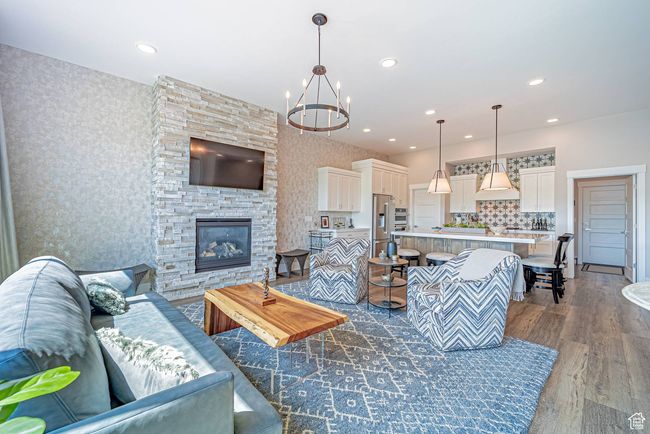 Living room with dark wood-style flooring, a chandelier, wallpapered walls, recessed lighting, and a fireplace | Image 10