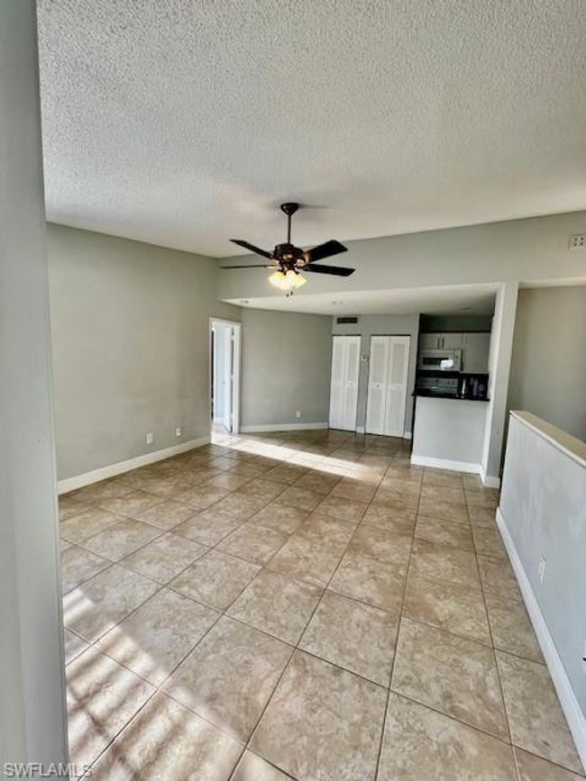Tiled empty room with a textured ceiling, ceiling fan, and baseboards | Image 23