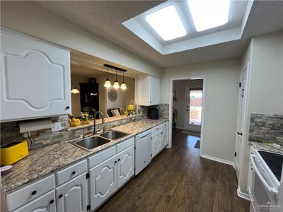 Kitchen with white appliances, sink, pendant lighting, white cabinets, and dark hardwood / wood-style floors | Image 2