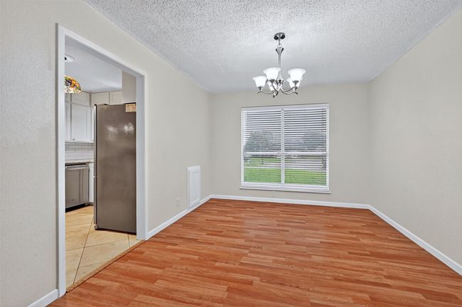 Unfurnished dining area with light wood-style flooring, a chandelier, and a textured ceiling | Image 6