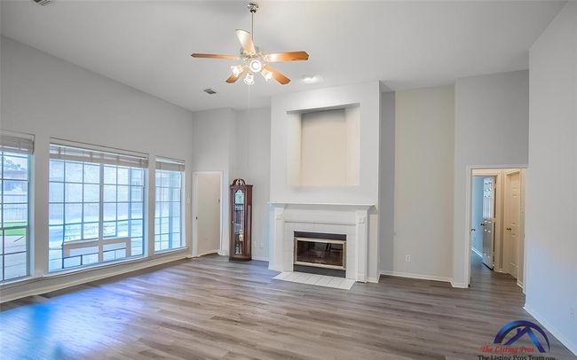 Bright and spacious living room with high ceilings, large windows, and a fireplace. Features modern flooring and a ceiling fan. Ideal for family gatherings. | Image 18