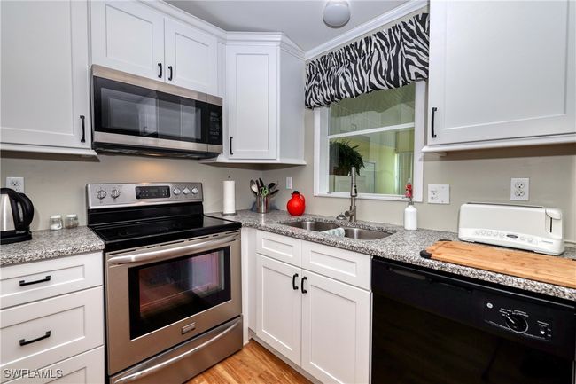 Kitchen with light stone countertops, white cabinetry, sink, stainless steel appliances, and light hardwood / wood-style floors | Image 8