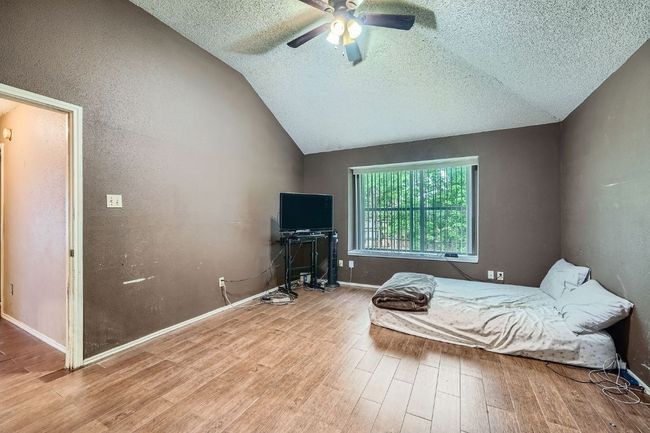 Bedroom featuring a textured ceiling, wood finished floors, lofted ceiling, and a ceiling fan | Image 15