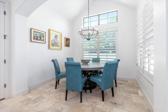 Dining area with stone tile flooring, a chandelier, baseboards, arched walkways, and high vaulted ceiling | Image 7