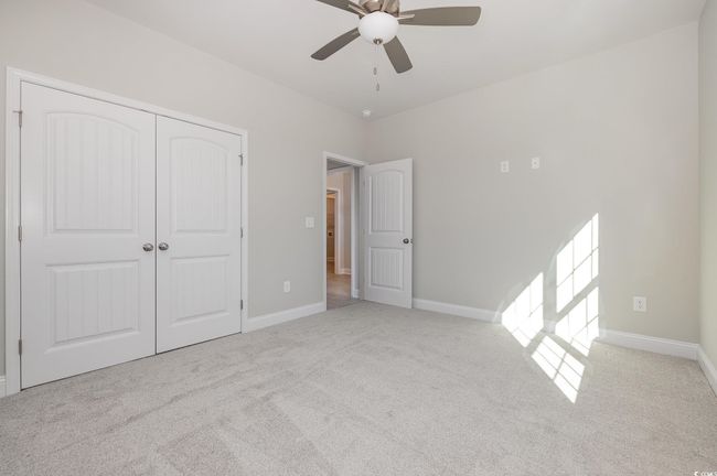 Unfurnished bedroom with ceiling fan, a closet, and light colored carpet | Image 22