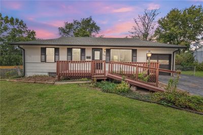 Ranch-style house with a wooden deck and a yard | Image 1