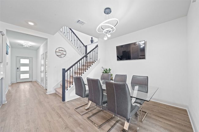 Dining space featuring visible vents, stairway, a chandelier, wood finished floors, and baseboards | Image 13