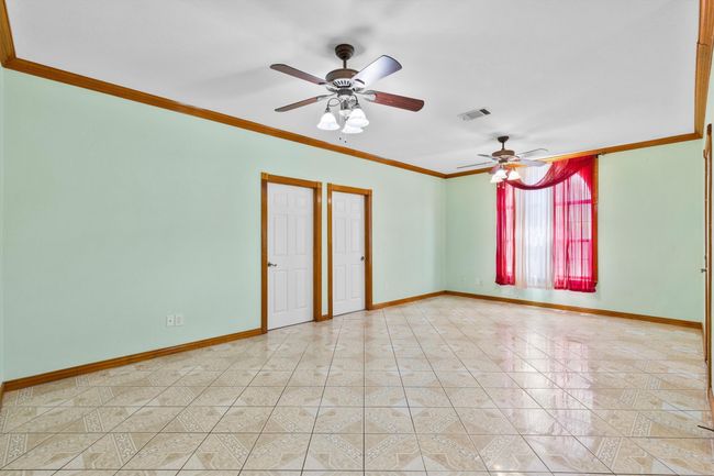 Empty room with a ceiling fan, baseboards, ornamental molding, and light tile patterned floors | Image 19