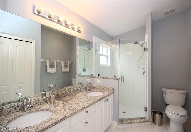 Bathroom with vanity, toilet, tile patterned floors, and a shower with door | Image 15