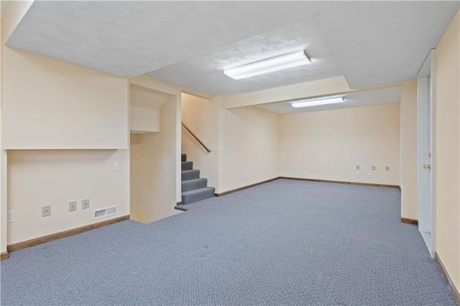 Finished basement with visible vents, baseboards, stairway, and carpet floors | Image 32