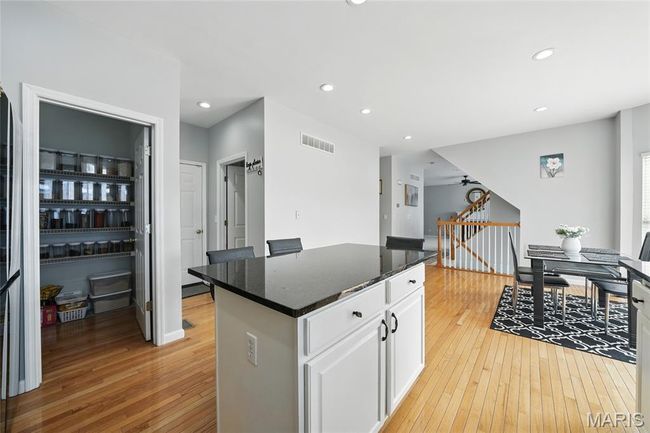 Kitchen featuring light wood-style floors, a kitchen island, white cabinetry, recessed lighting, and dark stone counters | Image 13