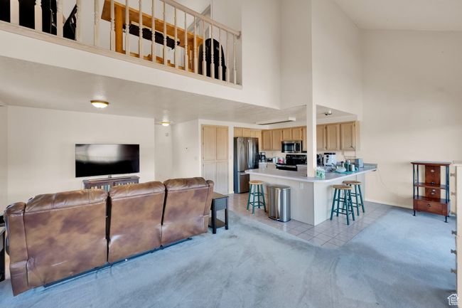 Living room featuring light carpet, baseboards, a towering ceiling, and light tile patterned floors | Image 6